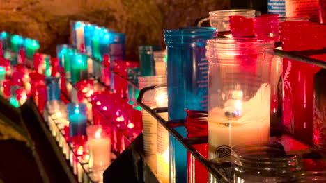 rows of candles burning in a church