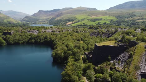 aerial view welsh woodland slate mining shaft and quarry lake orbiting snowdonia mountain valley