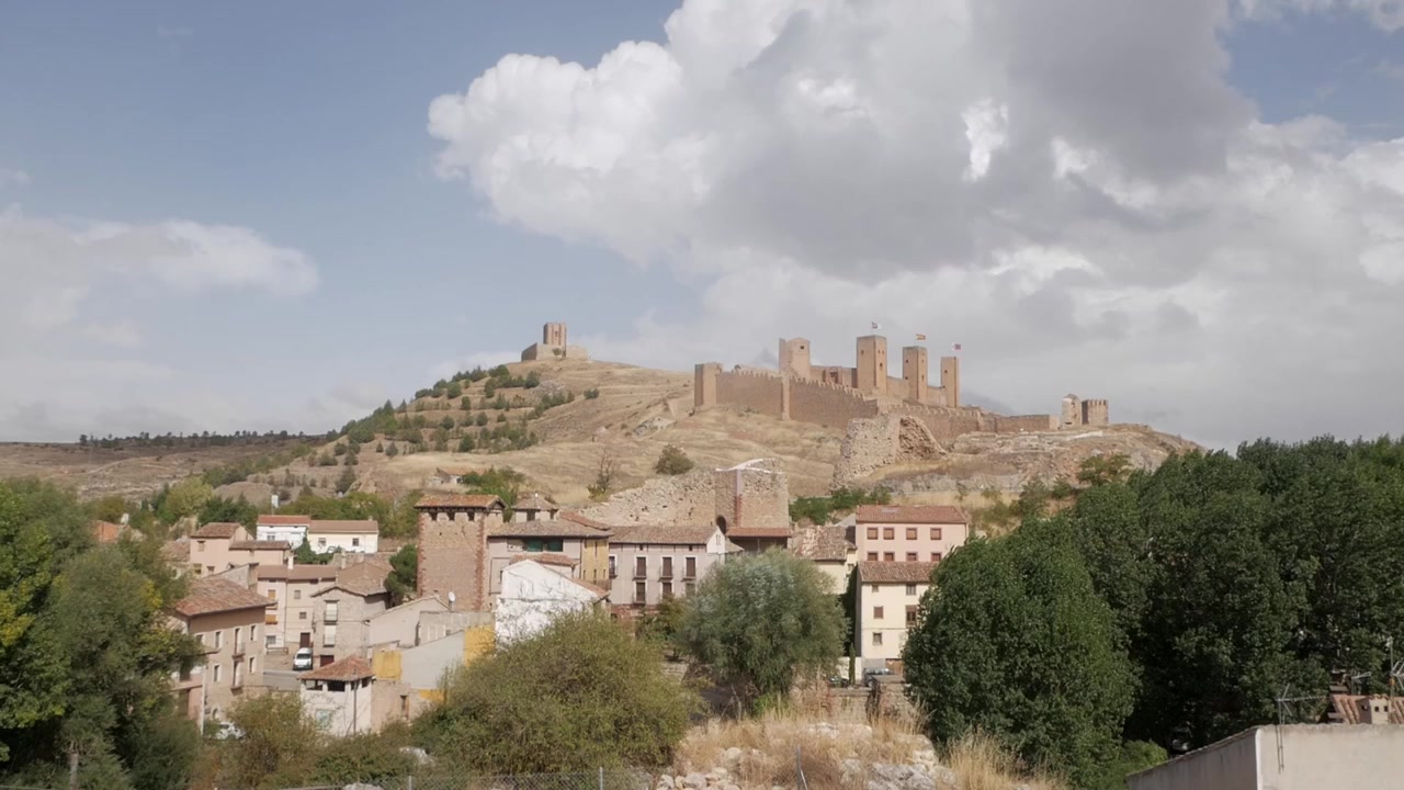 Ampia vista di una storica fortezza in cima a una collina sopra la città di Molina de Aragón sotto un cielo nuvoloso.