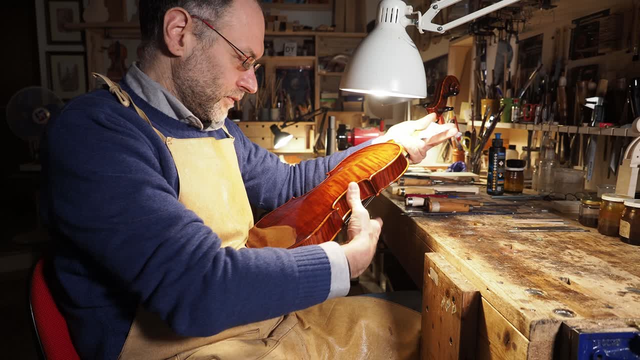 Portrait of luthier crafting a violin in artisan workshop, focus on woodworking, craftsmanship, tools and traditional creative process