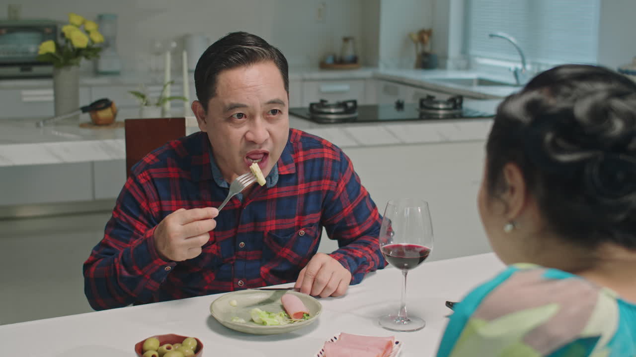 Aged Woman and Man Dining Together with Wine at Home Kitchen
