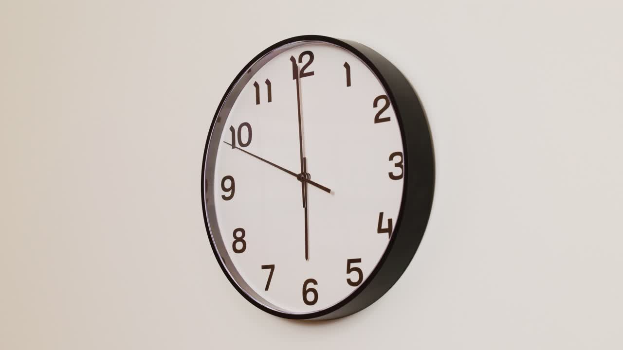 A close-up 4K shot of a black and white wall clock filling the frame, showing the time as 6:00.