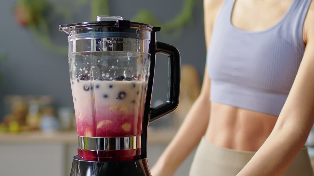 Fit Woman Making Smoothie in Kitchen Blender