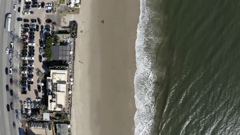 aerial view of a coastal beach with road, cars, and buildings