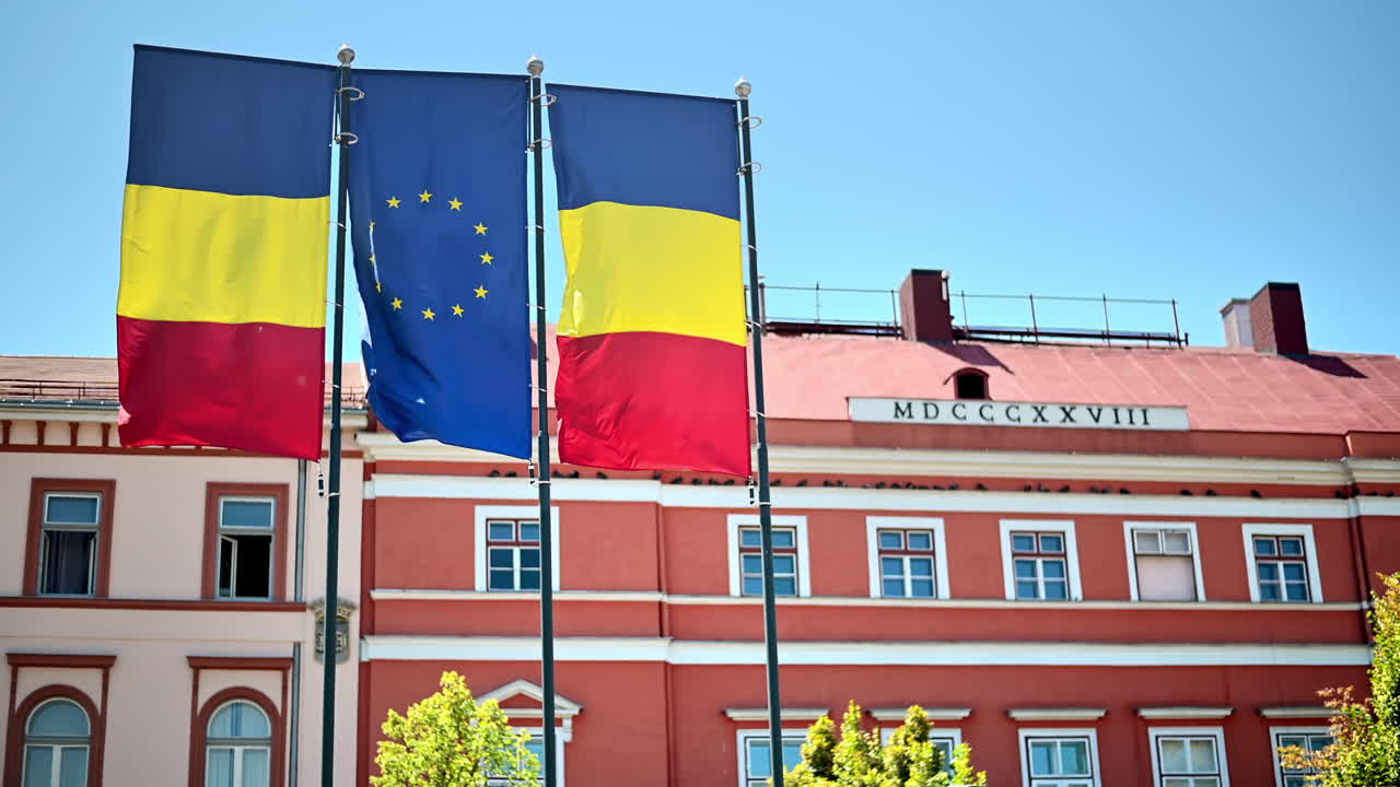 Romanya, Cluj merkezinde iki ulusal bayrak ve bir Avrupa Birliği bayrağı. Arka planda klasik bir bina