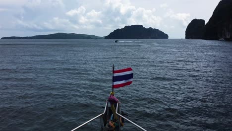 thai flag blowing in the wind on the front bow of boat near koh phi phi islands