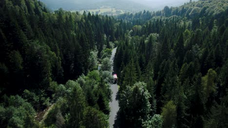 4k drone shot of fire truck driving in stunning forest landscape scenery