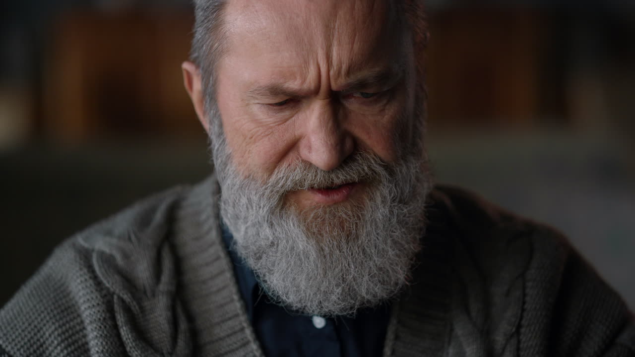 Closeup upset old man face listening during video call at home