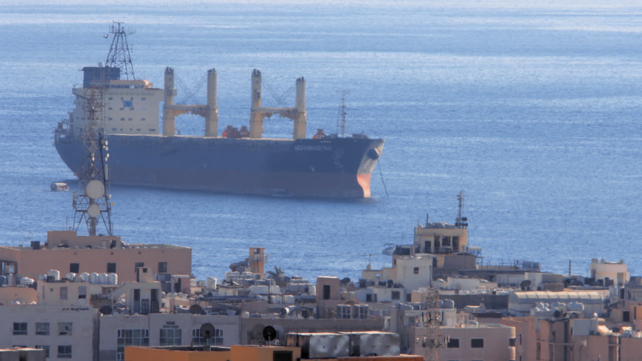 Cargo ship docking in the Gulf of Aqaba with houses in foreground. 4K