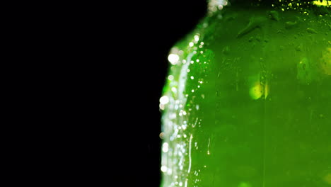 part of a bottle of cold beer drops of condensate flow down the glass on a black background the free