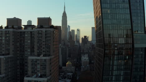 Adelante-Vuelan-Entre-Edificios-De-Apartamentos-De-Gran-Altura.-Vista-Reveladora-De-La-Torre-De-Oficinas-Y-El-Icónico-Edificio-Empire-State.-Manhattan,-Ciudad-De-Nueva-York,-Estados-Unidos