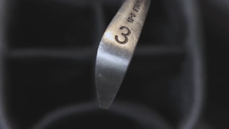 close-up shot of 3 iron golf club being place into a golf bag after being used