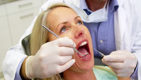 dentist examining a female patient with dental tools