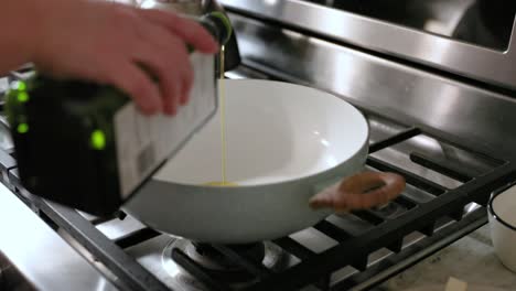 woman pouring olive oil into frying pan in 4k