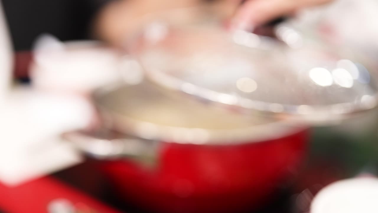 manos preparando una olla caliente en una olla roja