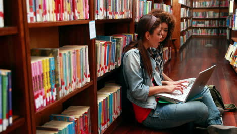 Lächelnde-Studenten-Lernen-Zusammen,-Sitzen-Auf-Dem-Boden-In-Der-Bibliothek