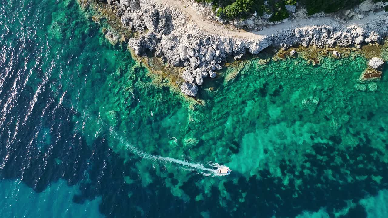 лодка, пересекающая кристально чистые воды недалеко от острова корфу, яркий день, взгляд с воздуха