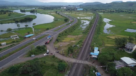 aerial view of indian railway track and indian highway running parallel in one shot with cargo freight train and locomotive passing