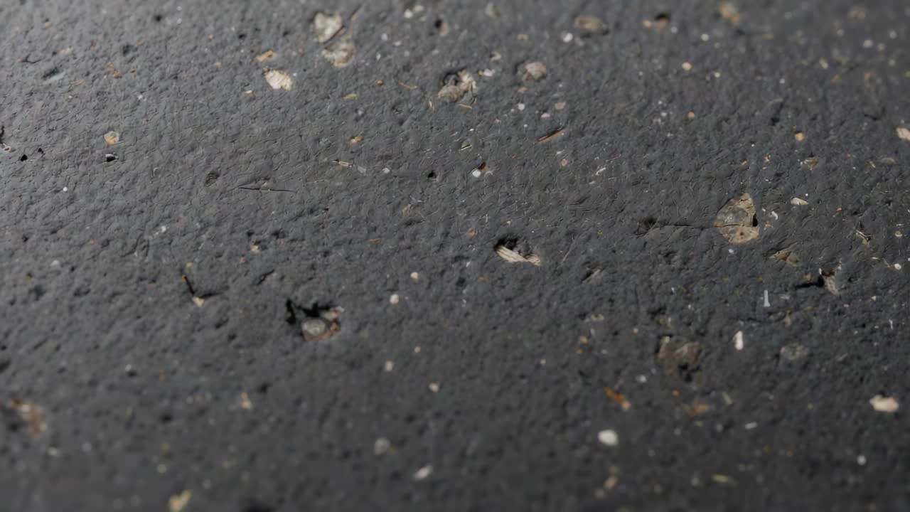 Panning camera revealing textured coated surface at close range examining light flakes and pits