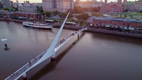 revealing aerial of pedestrian woman's bridge, puerto madero at sunset