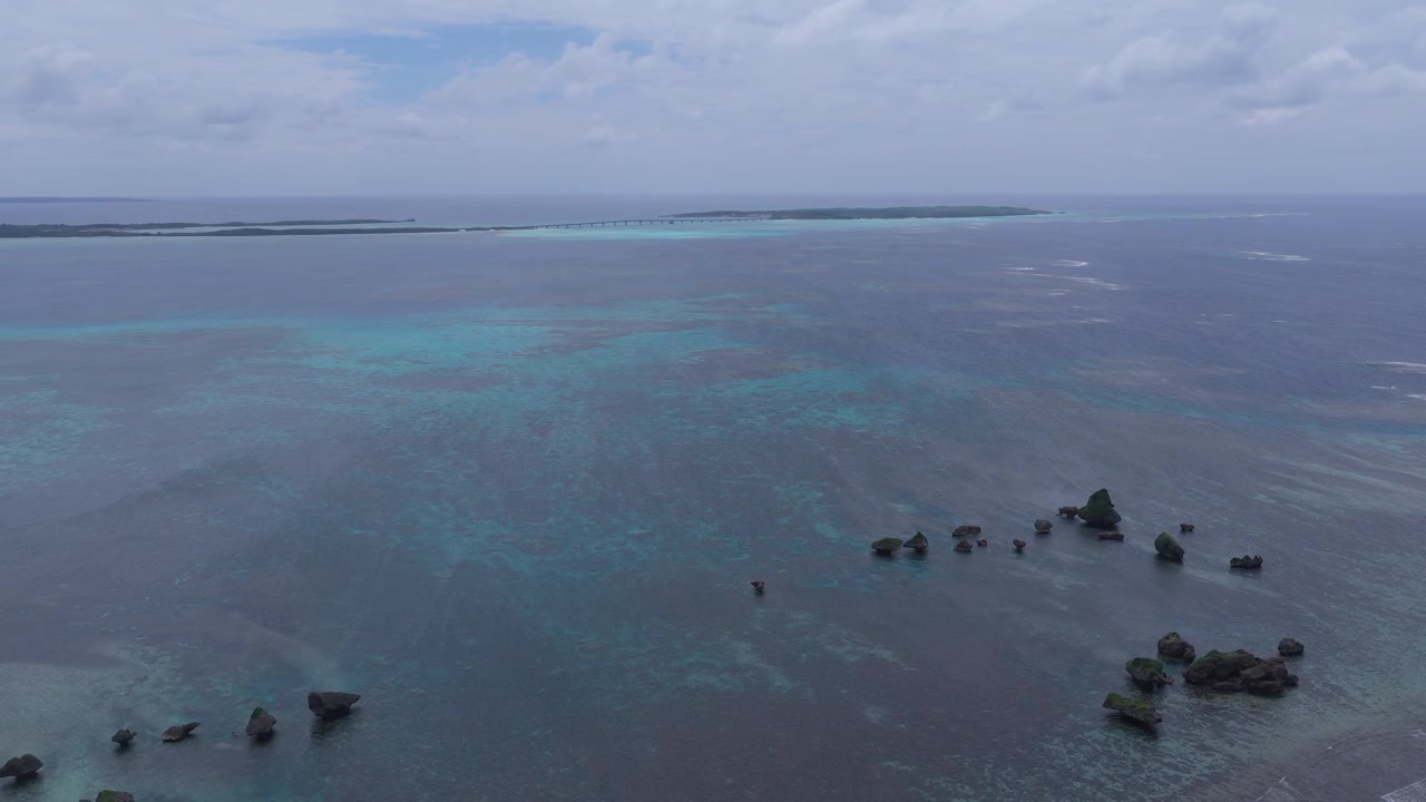 Riprese aeree orizzontali che panoramicano a sinistra mentre si spostano a destra sopra il mare aperto e le rocce di Kigan vicino all'isola di Ogami, Miyako, Okinawa, Giappone