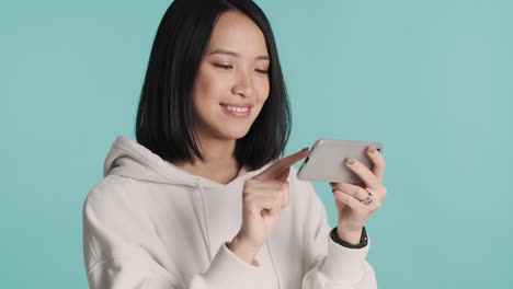 asian woman watching online video on smartphone and laughing.