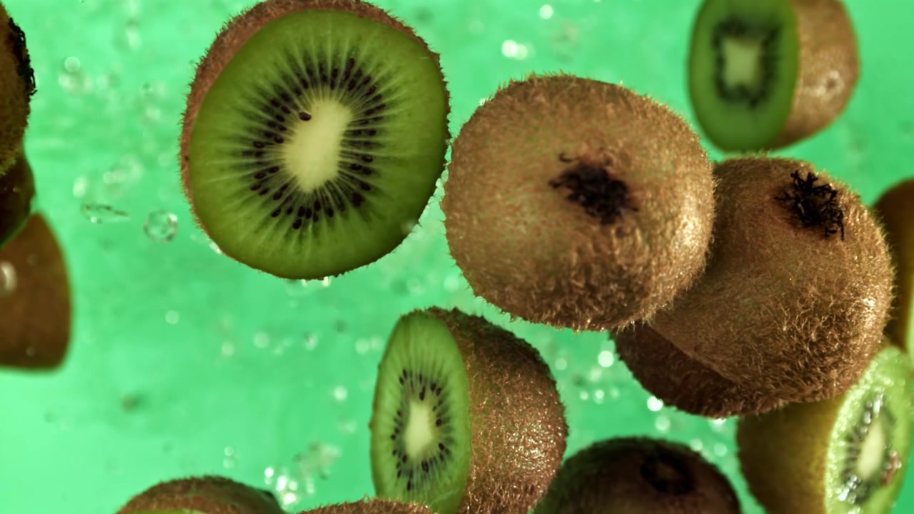Kiwis frescos con salpicaduras de agua sobre fondo verde en cámara lenta