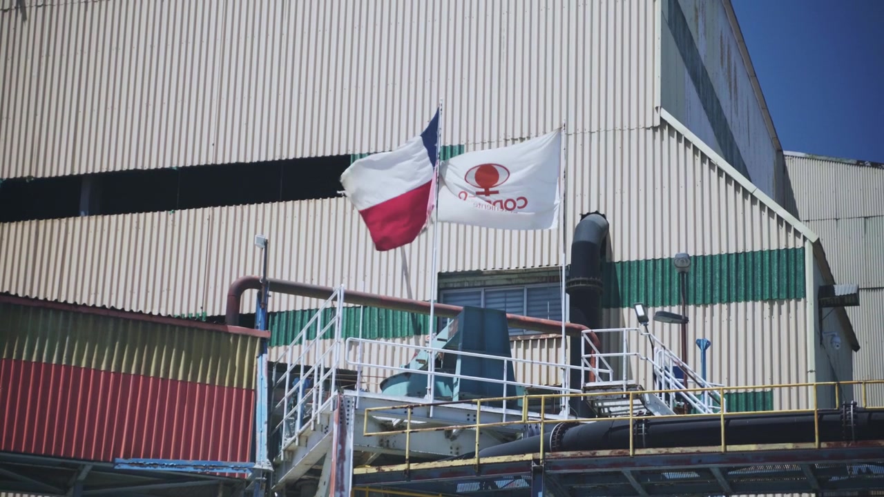 Banderas de Chile y Codelco ondeando fuera de las instalaciones industriales en la mina de cobre El Teniente en Rancagua, Chile. Metraje editorial que muestra la identidad minera nacional y corporativa.