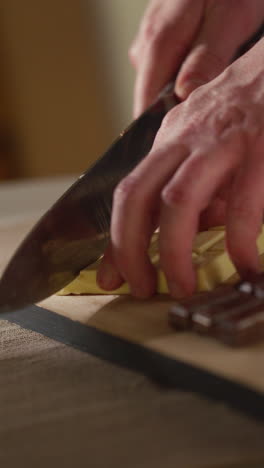 vertical video of person cutting bars of milk plain and white chocolate into smaller pieces with knife 1