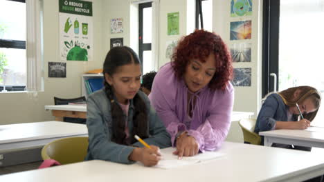 female teacher guiding girl with homework in classroom, both focused and engaged, at school