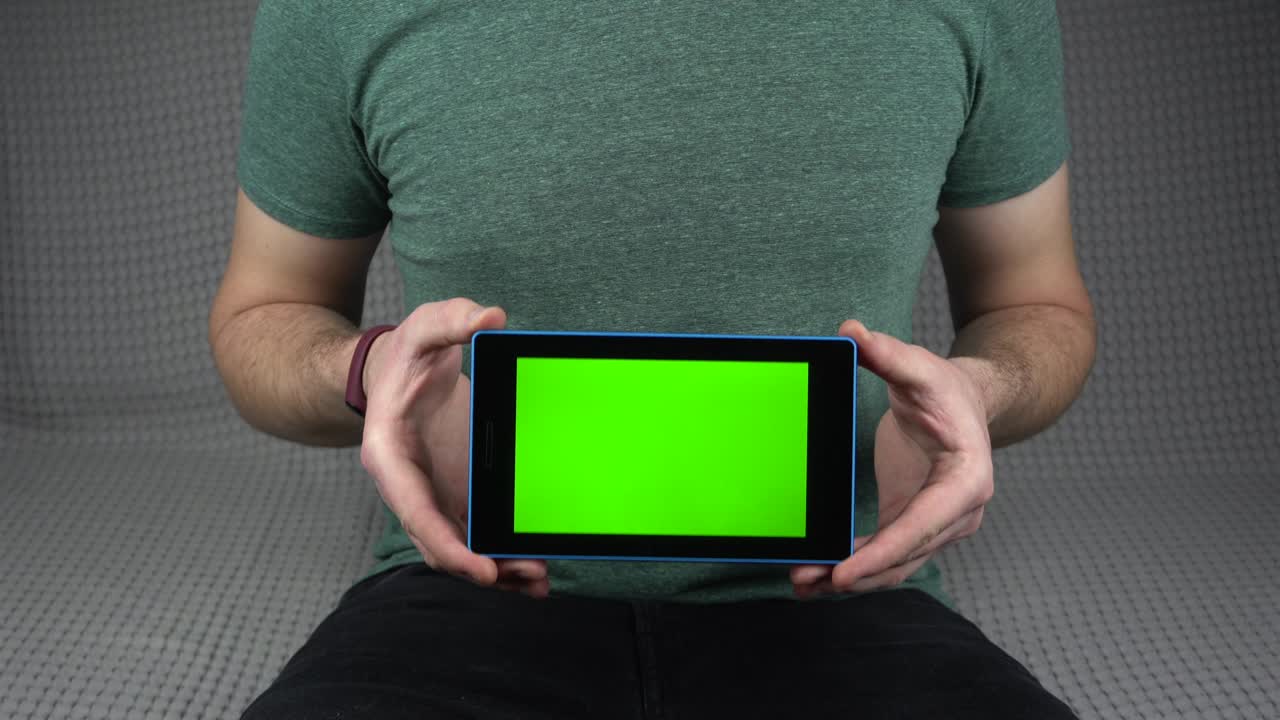 imágenes de un hombre mostrando una pantalla verde en la tableta mientras está sentado en el sofá