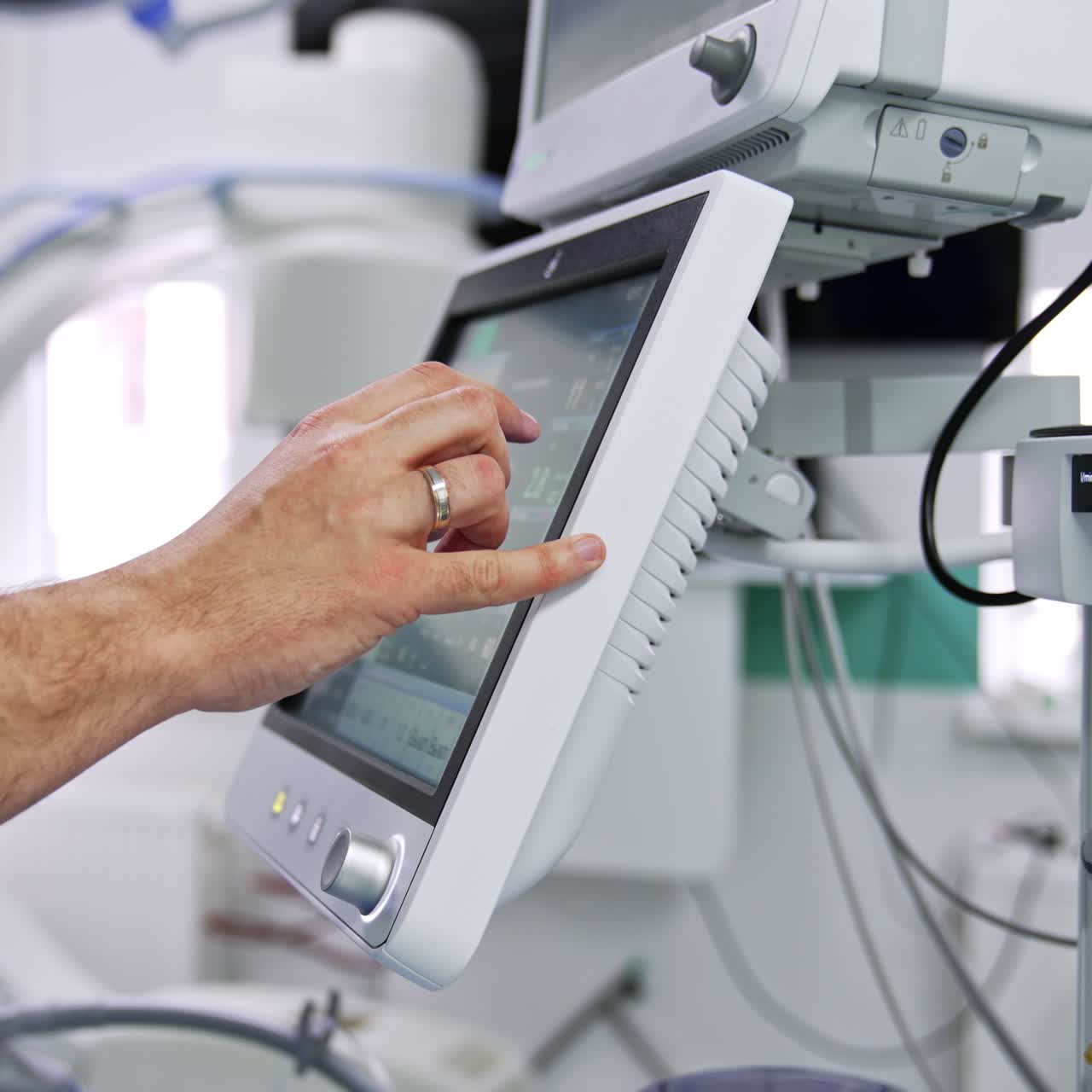 Male doctor standing near the screen of lung ventilation machine. Professional switches on the equipment getting ready for operation