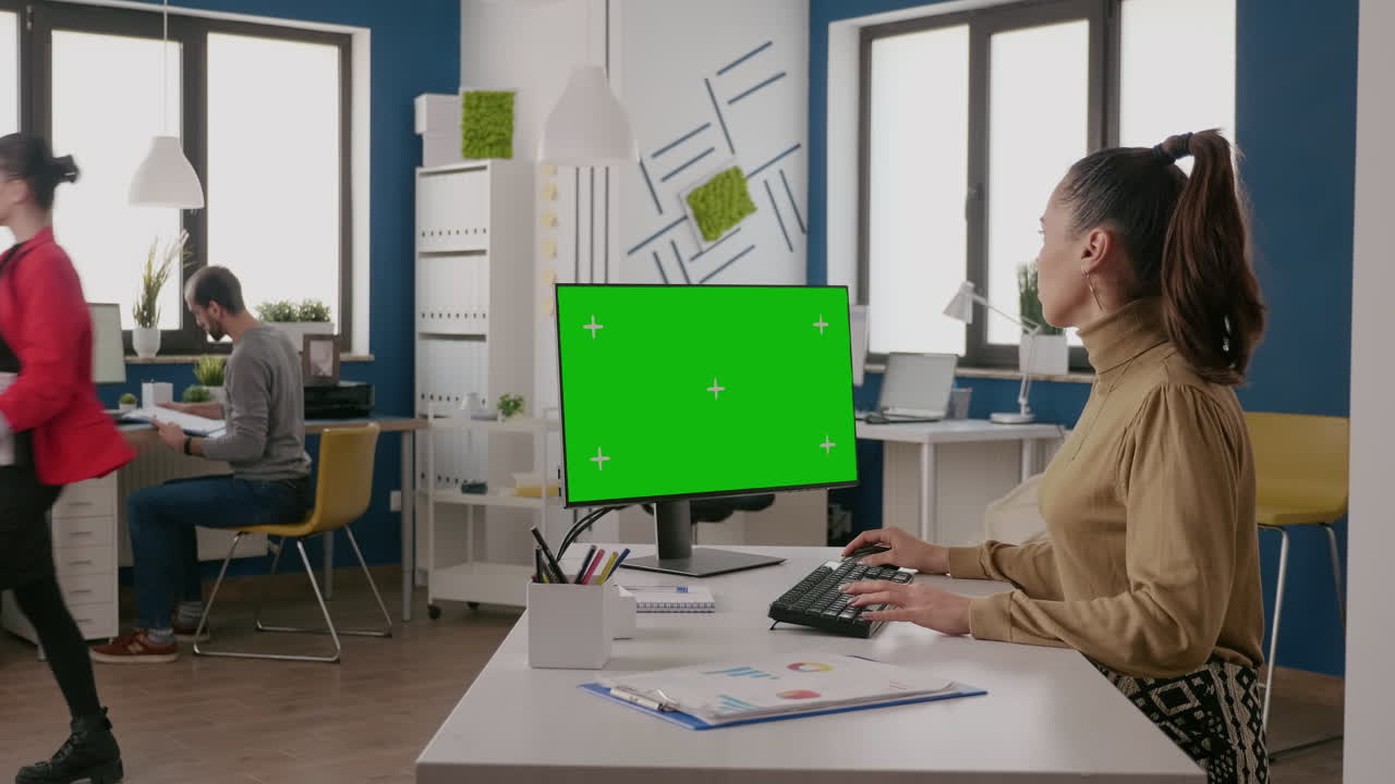 Donna che utilizza un computer con schermo verde isolato alla scrivania