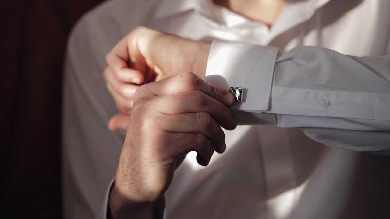잘생긴 신랑이 수갑을 수갑구이 있는 셔츠에 고정시킨다. 사업가