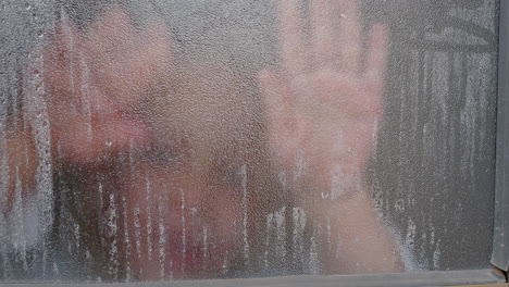 kid wiping steamy window to look outside