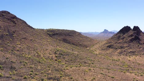 Aerial-slow-pan-to-left-from-butte-to-desert-mountainside-with-a-view-of-red-mountain,-McDowell-Mountain,-in-the-gap-between-the-butte-and-mountainside,-Salt-River-Indian-Reservation,-Scottsdale,-Az