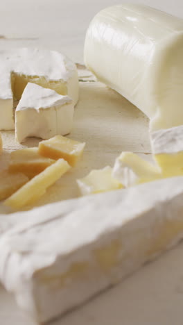 video of assorted hard and soft cheeses on rustic white wooden table top