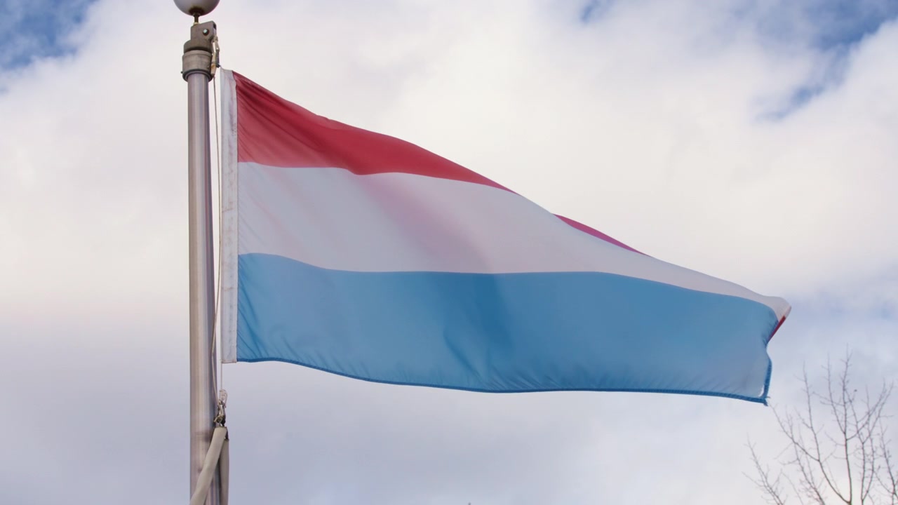 Vlag van Luxemburg wapperend in de wind tegen een blauwe lucht