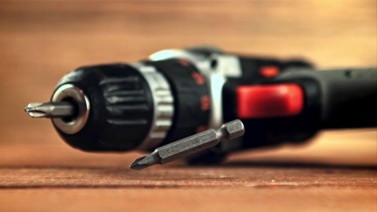 Screwdriver Bit Dropping onto Wooden Surface Next to Cordless Drill