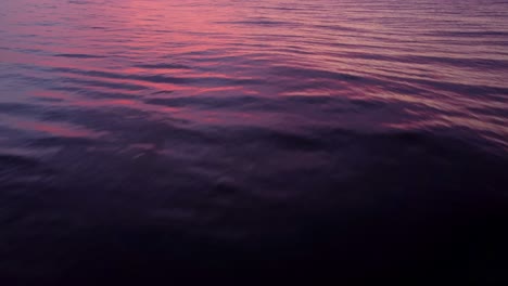 drone flight over a calm sea focusing on the ocean waves with an epic sunset sky