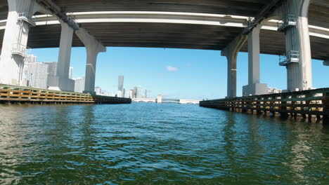 Aufnahme-Von-Einem-Kleinen-Boot-Aus,-Das-Unter-Der-Biscayne-Bay-Bridge-Hindurchfährt,-Mit-Miami-Im-Hintergrund