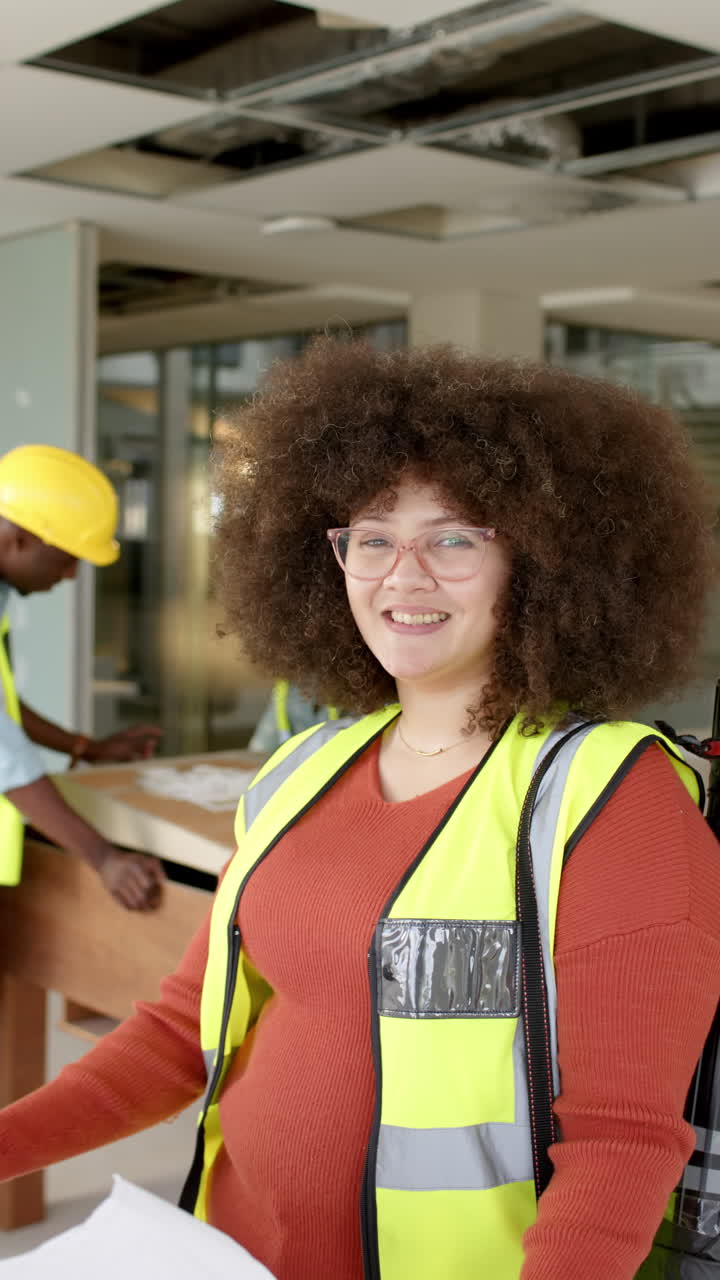 Vertical video of casual biracial female architect looking at plans, slow motion, copy space