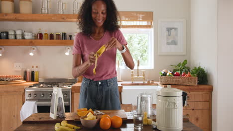 smiling woman in kitchen peeling banana for healthy breakfast preparation, at home