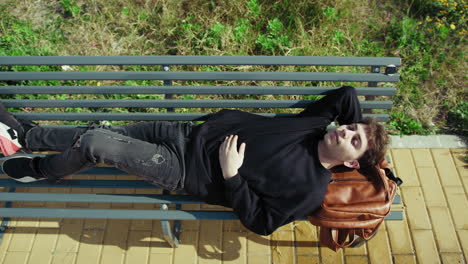 tired student sleeping on the park bench after school