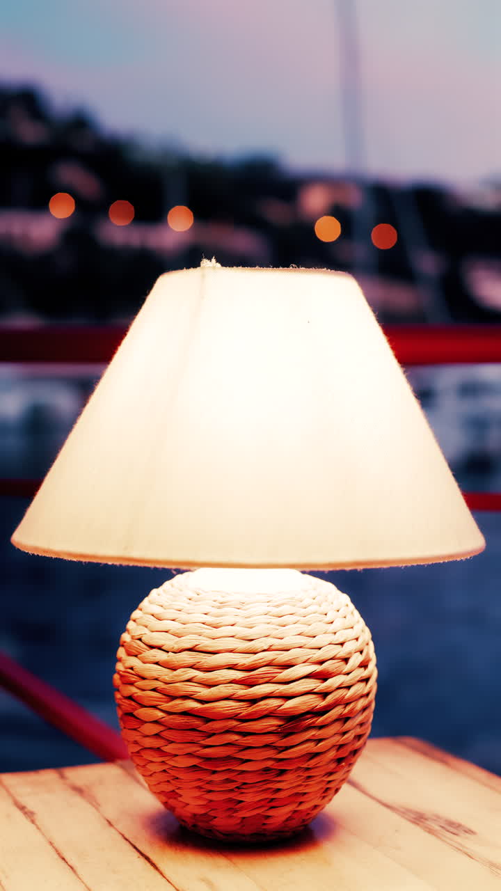Close up view of a lamp on a table at a restaurant near a port in the south of France in the evening. Vertical