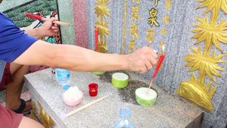 person lighting incense sticks at a grave site.