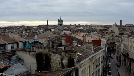 french city of bordeaux rooftops with cailhau city gate and pigeons flying, aerial pedestal lowering shot