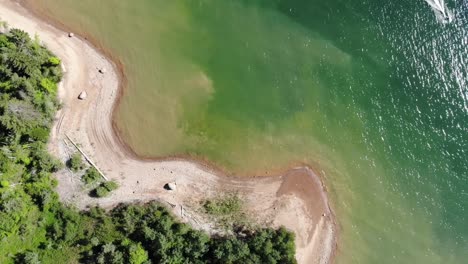 aerial footage over a beach on a green lake, looking straight down