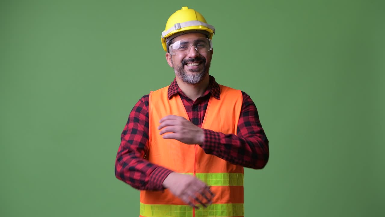 Handsome Persian bearded man construction worker wearing protective glasses with arms crossed