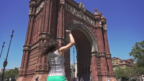 Slow-motion-of-cheerful-and-beautiful-girl-spinning-around-against-Arc-de-Triomf